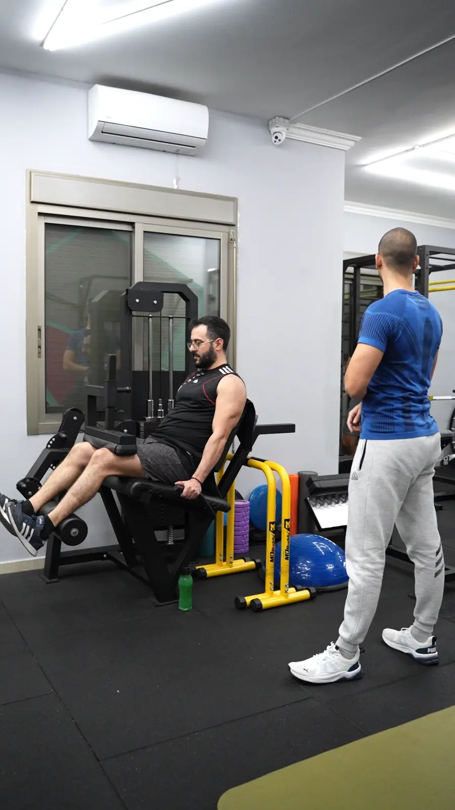 A coach supervising a client on a leg machine