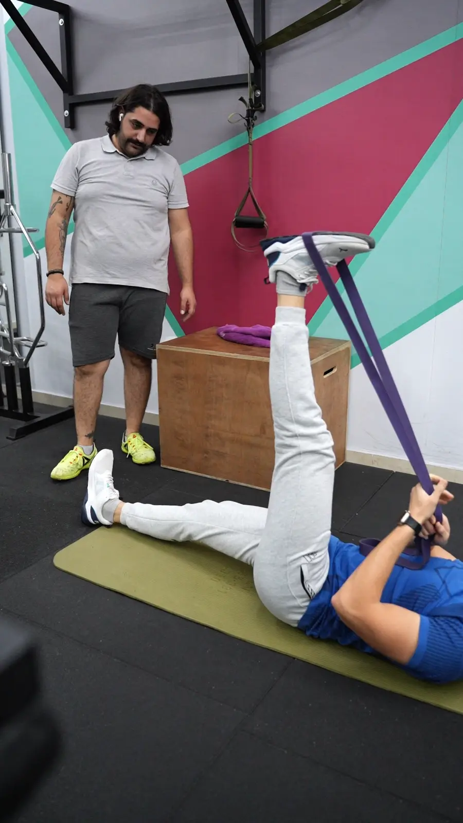 A coach guiding a client through a banded leg exercise